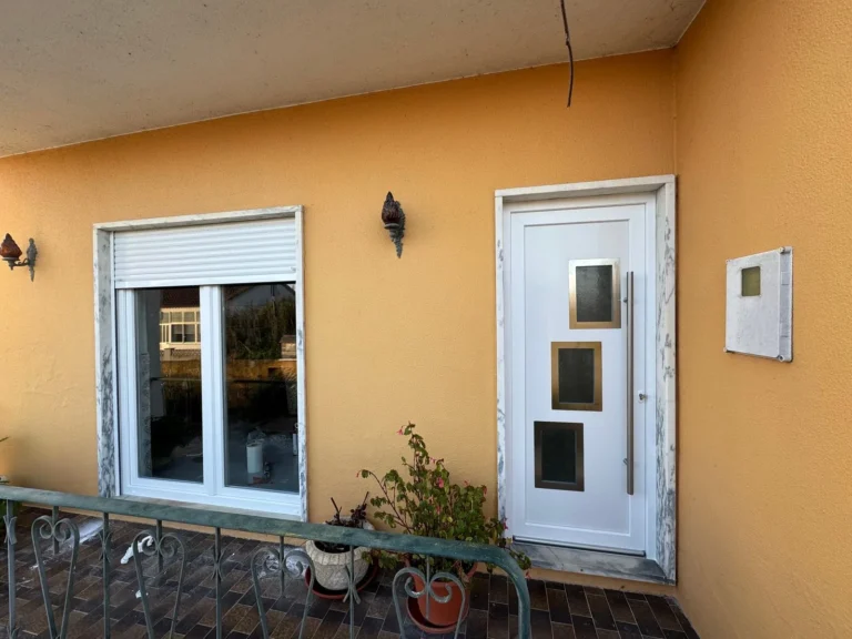 Porta envidraçada e janela em PVC branco em fachada laranja