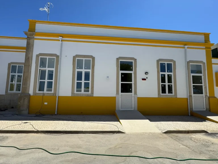 Fachada tradicional algarvia com friso amarelo e janelas novas em PVC