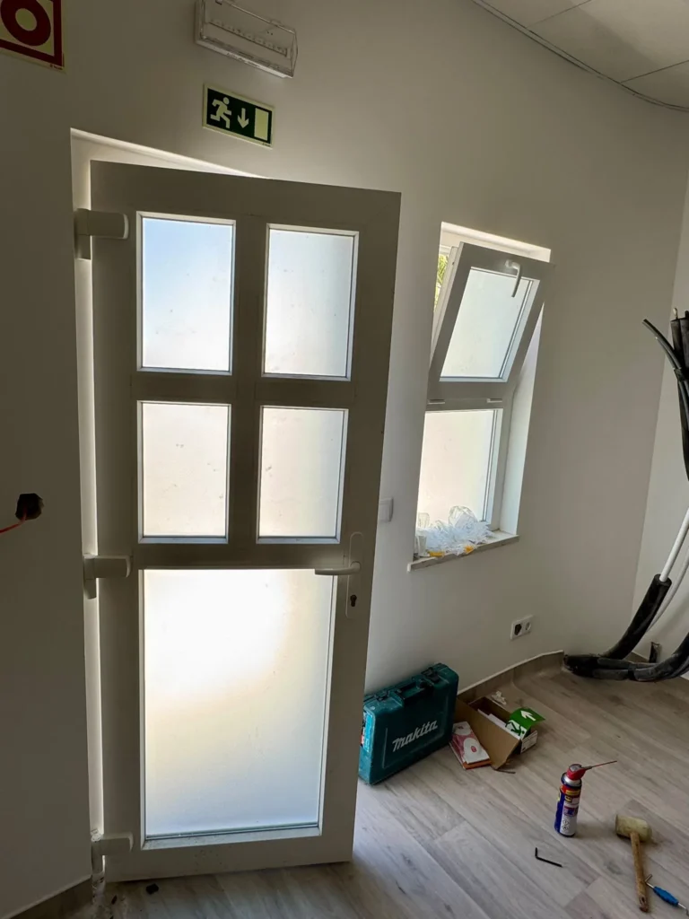 Porta em PVC branco com vidro fosco, ainda em obra