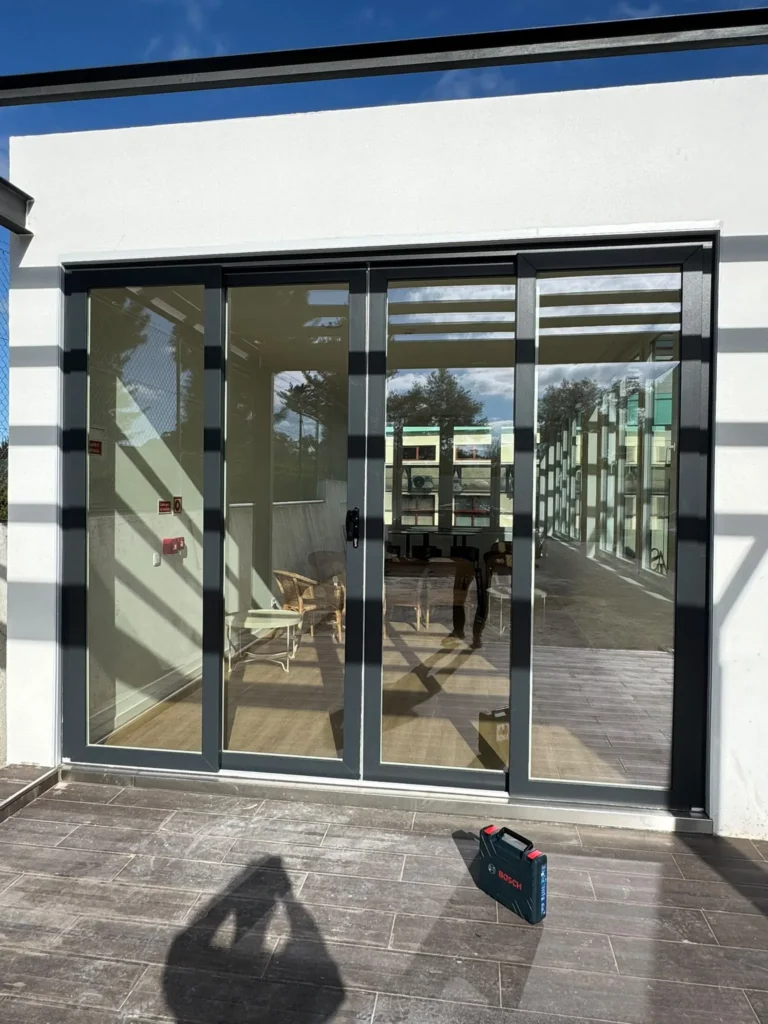 Envidraçado de correr em caixilharia escura sob pérgola de terraço