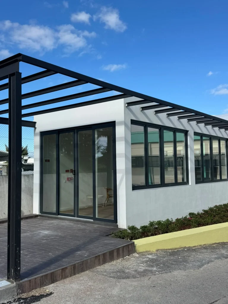Edifício com frente envidraçada em caixilharia escura e pérgola