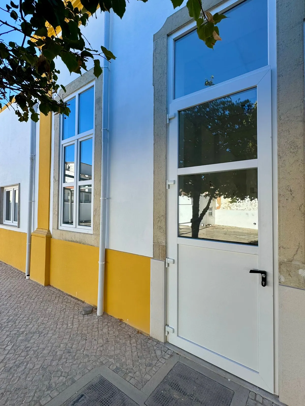 Fachada algarvia com barra amarela e porta de PVC branca envidraçada
