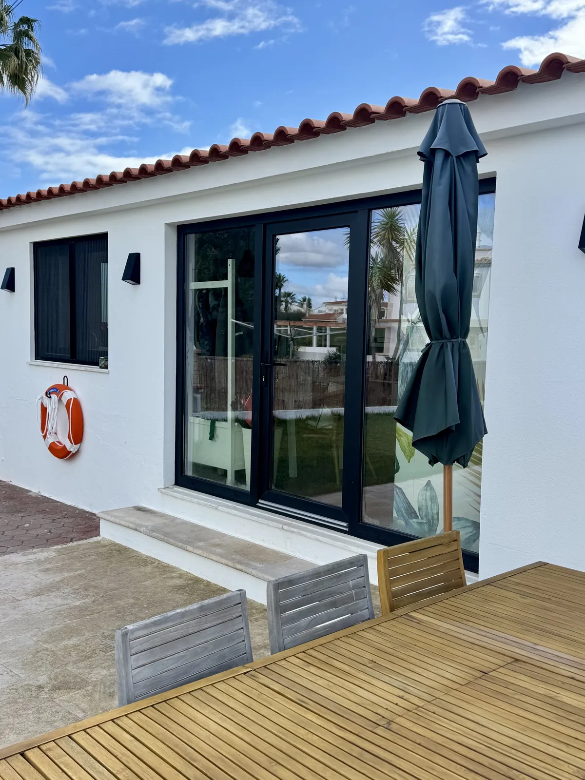 Porta de correr em PVC com moldura escura, aberta sobre um deck de madeira